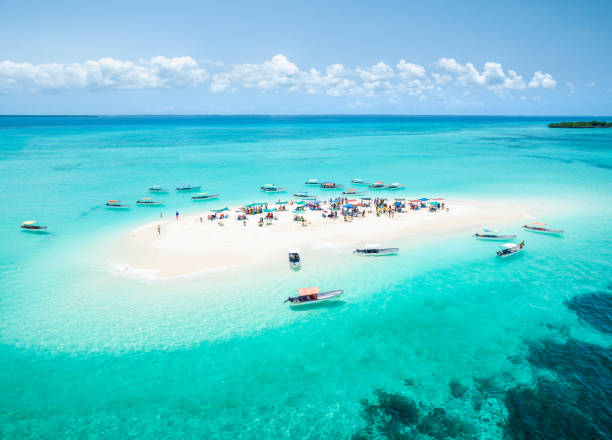 Aerial view showcasing the vibrant Kizimkazi Pungume Island SandBank in Zanzibar, surrounded by turquoise waters and dotted with boats and visitors under a clear blue sky